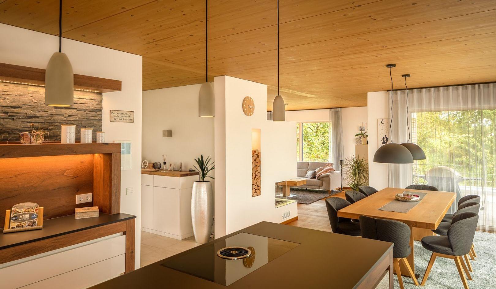 Moderne offene Küche und Essbereich mit Holzelementen und großen Fenstern.