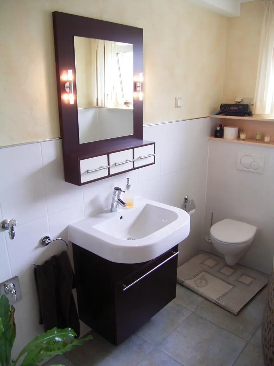 Modernes Badezimmer mit Waschbecken, Spiegel, WC und hellen Fliesen.