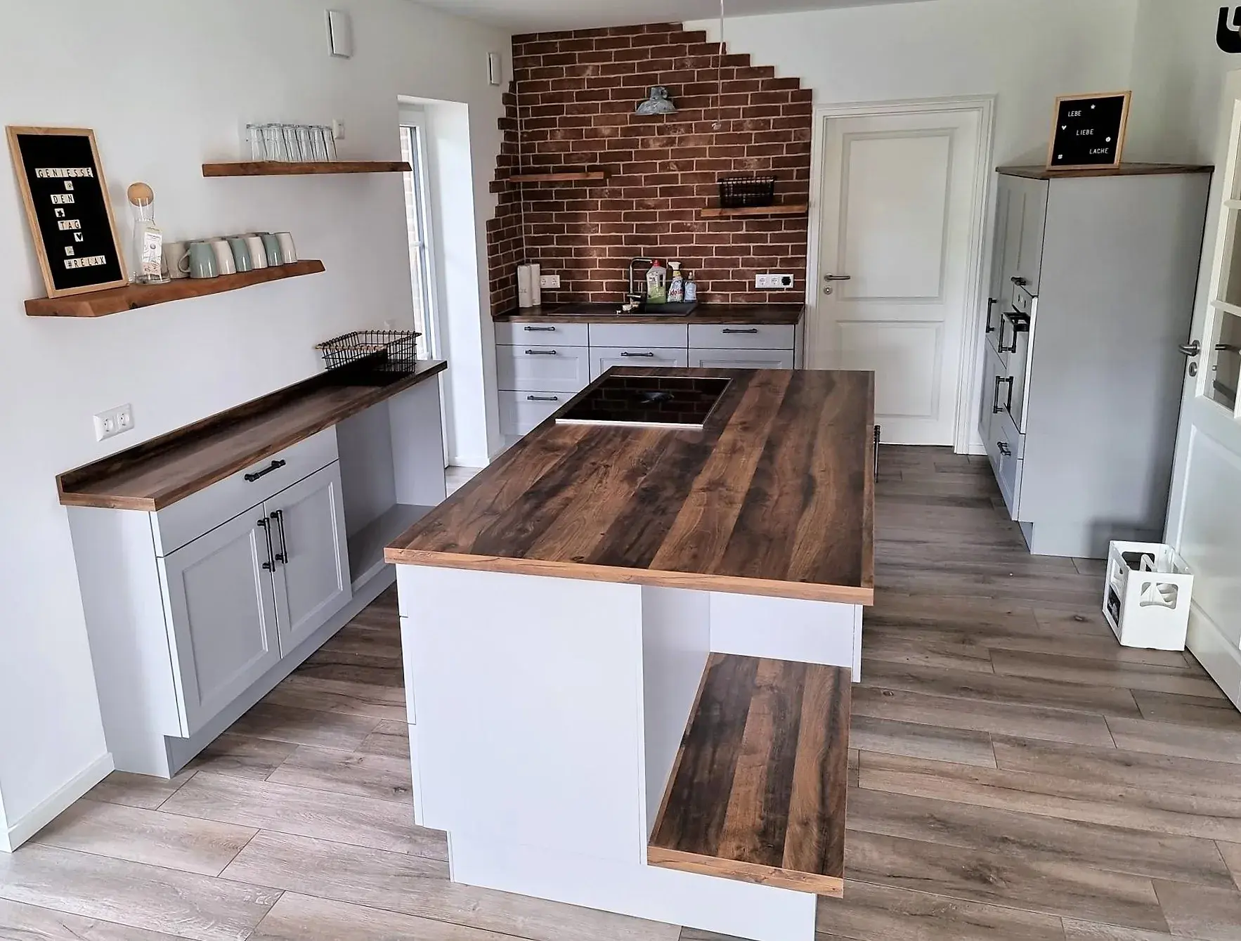 Moderne Küche mit Kücheninsel und Holzakzenten, eine Wand mit Ziegelsteinoptik.