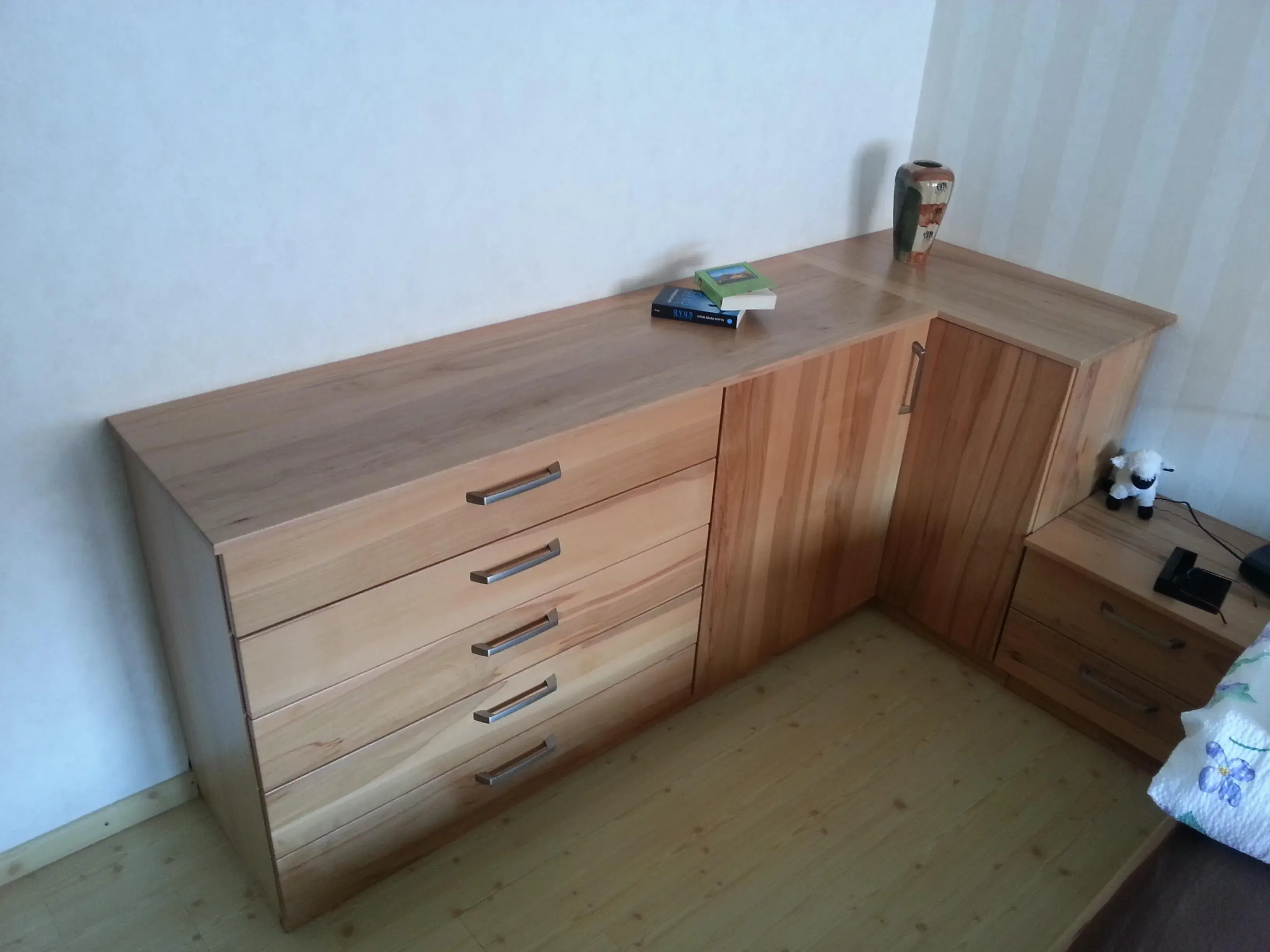 Holzkommode mit mehreren Schubladen, darauf liegen Bücher und Dekorationsartikel.