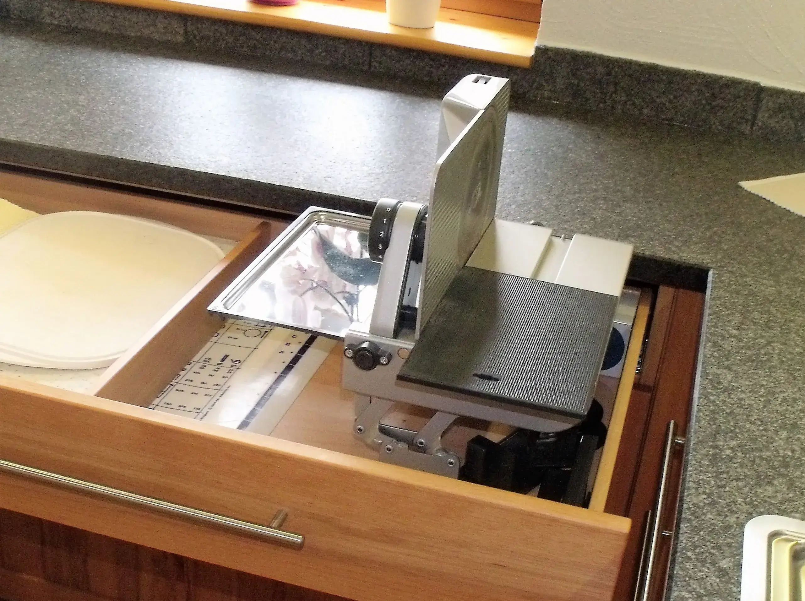 Allesschneider in einer geöffneten Küchenschublade auf Granit-Arbeitsplatte