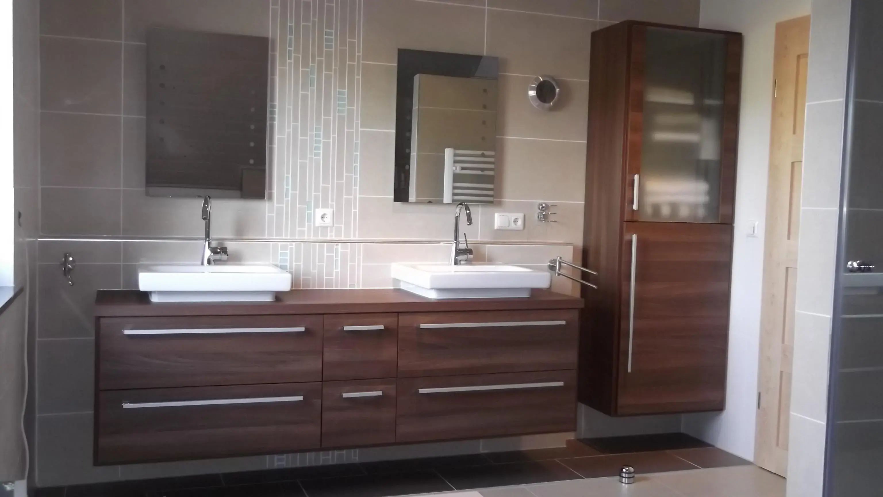 Modernes Badezimmer mit zwei Waschbecken und Holzunterschränken.