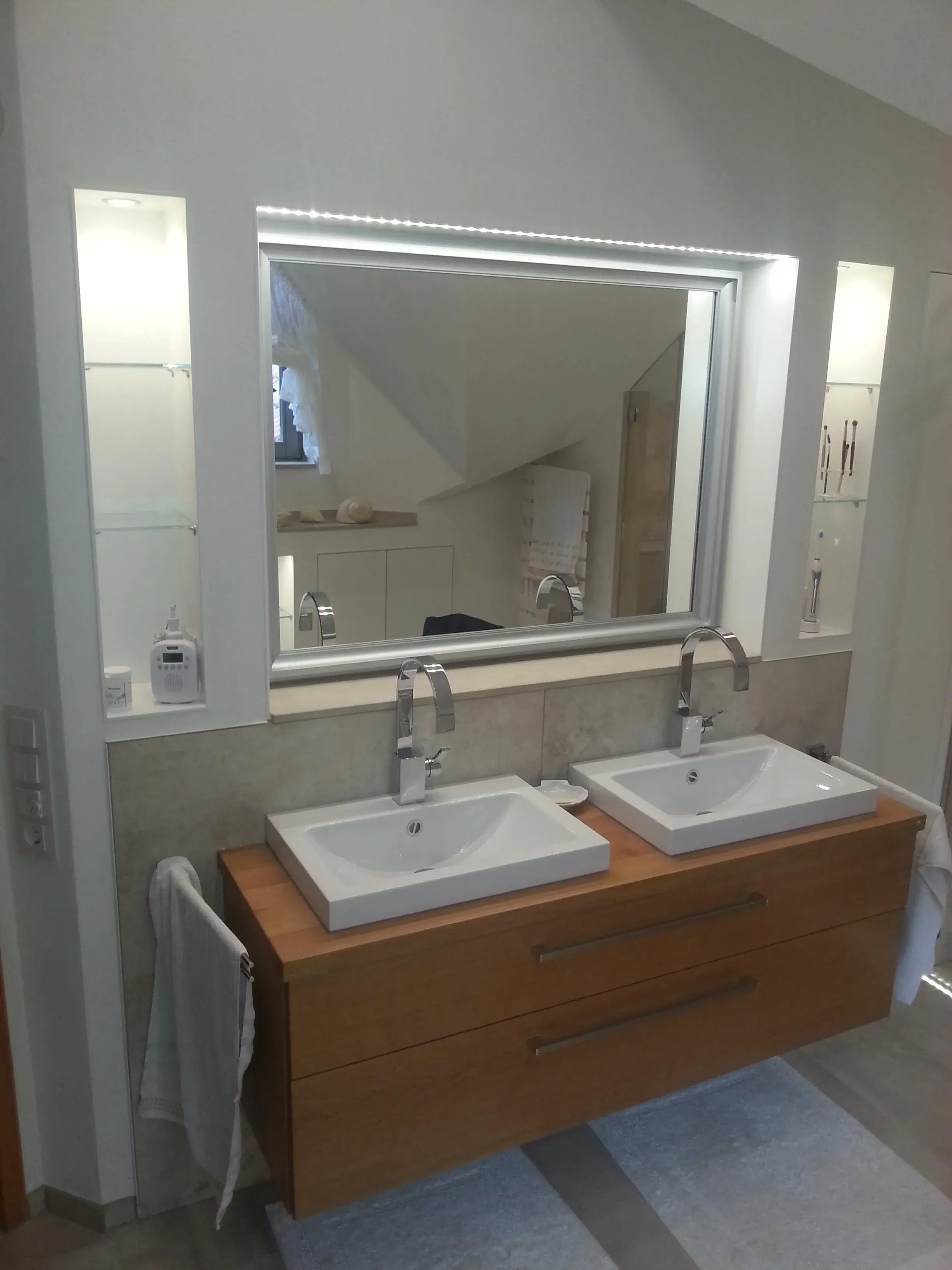 Modernes Badezimmer mit zwei Waschbecken, großem Spiegel und Holzunterschrank.